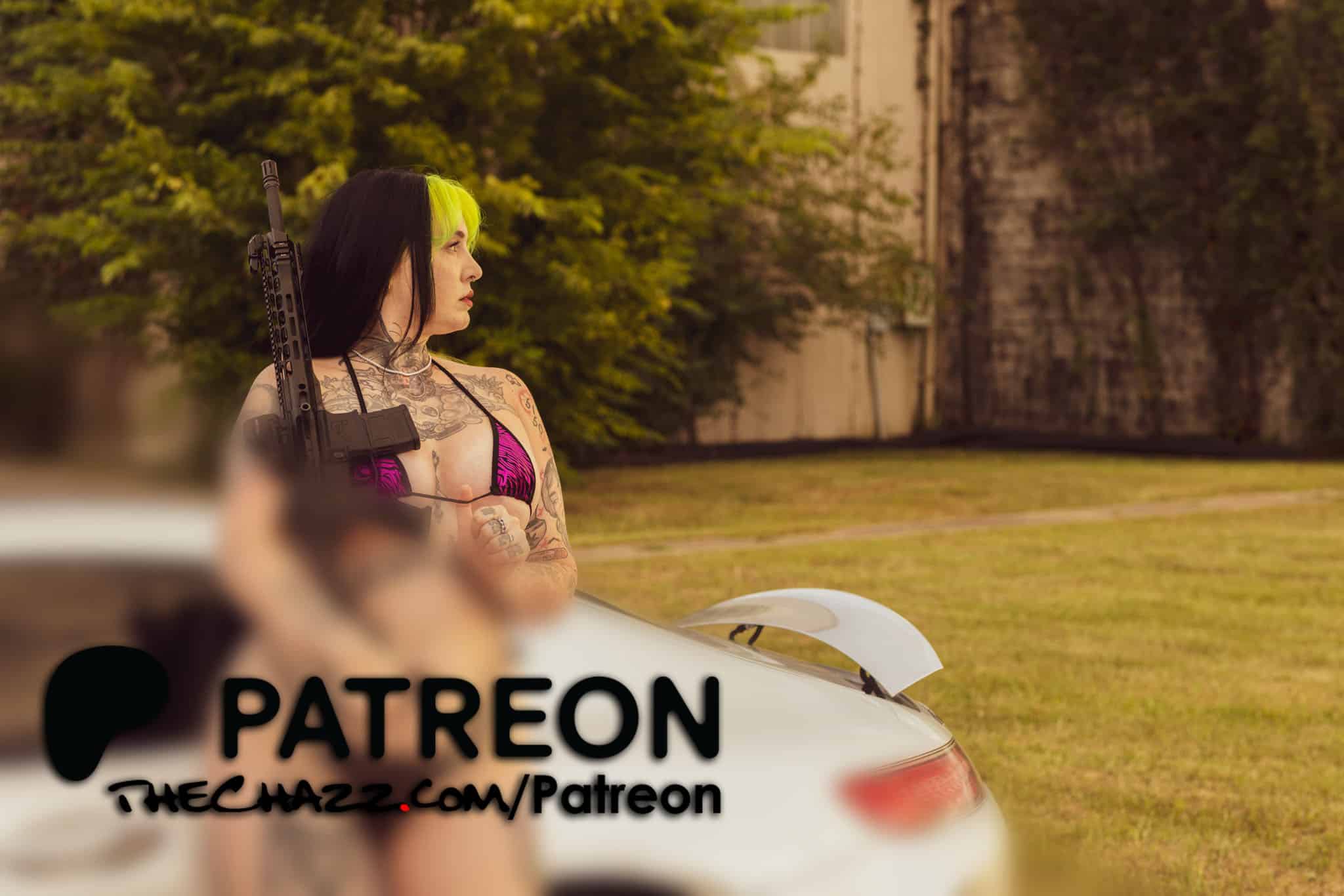 Tattooed woman with a firearm leaning on a car outdoors, edgy style, TheChazz.com.