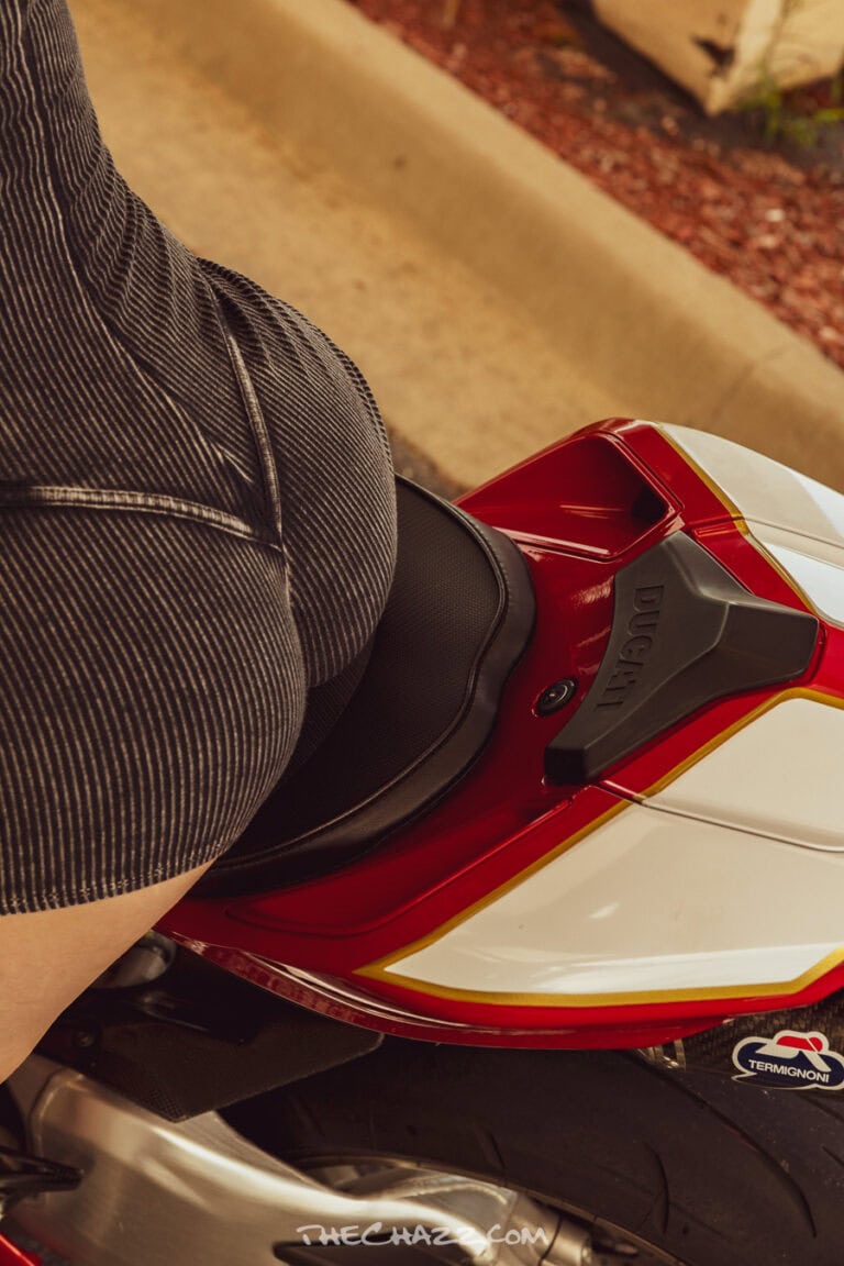 Alisa posing with a red Ducati motorcycle in a black romper and boots.