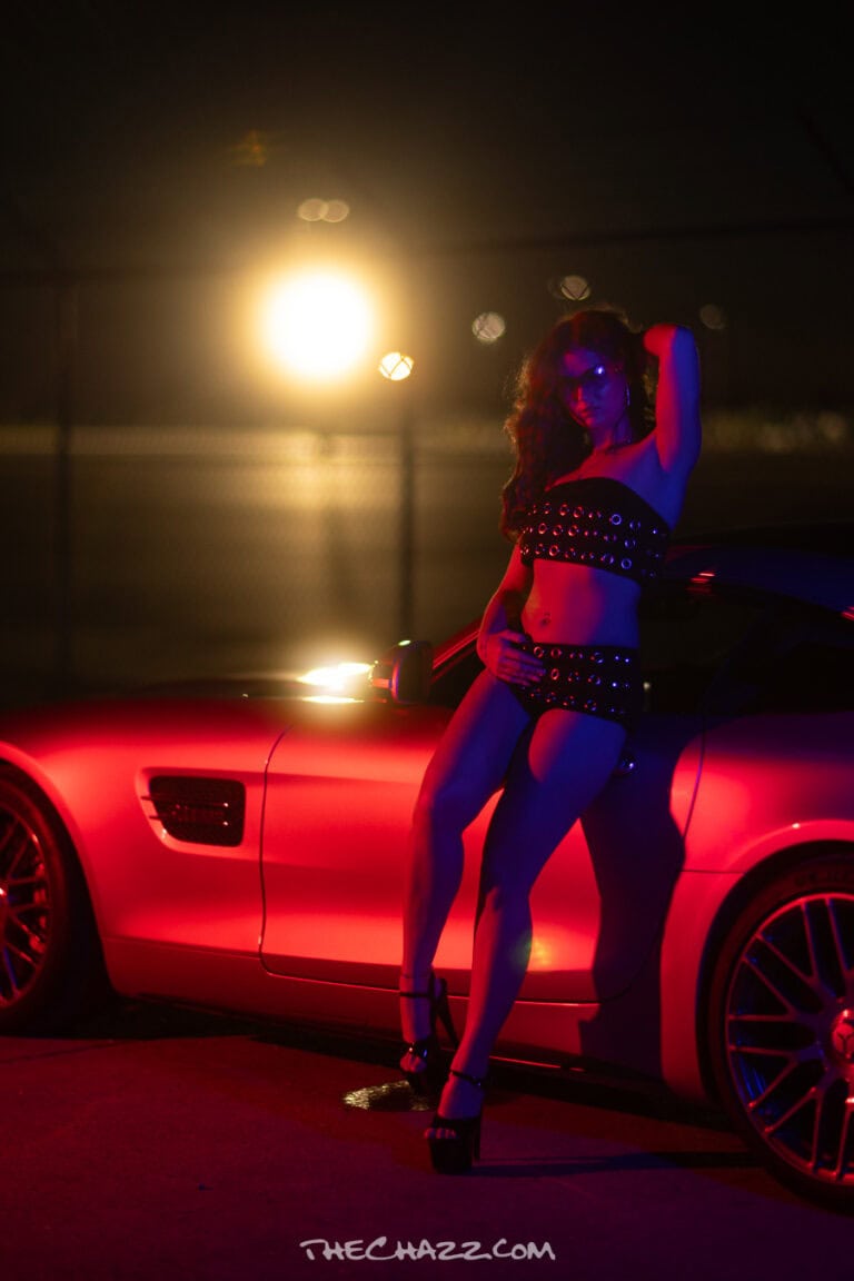 Marissa poses with a silver Mercedes-AMG GTC in an industrial setting.